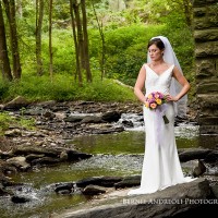 Creative Bridal Session color photograph with bride in an elegant full length pose standing on a flat rock in a stream