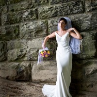 Creative Bridal Session color photograph with bride in an elegant full length pose on a sand bar under a stone railroad tressel